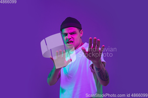 Image of Caucasian man\'s portrait isolated on purple studio background in neon light