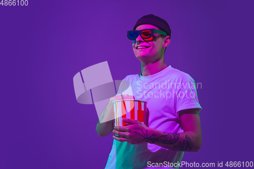 Image of Caucasian man\'s portrait isolated on purple studio background in neon light, cinema concept