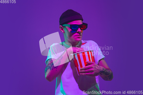 Image of Caucasian man\'s portrait isolated on purple studio background in neon light, cinema concept