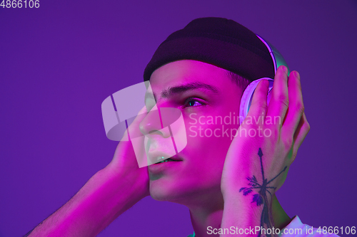 Image of Caucasian man\'s portrait isolated on purple studio background in neon light