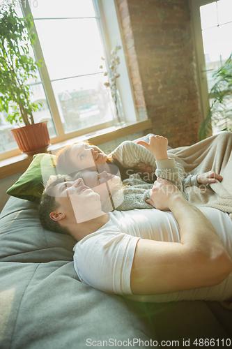 Image of Family spending nice time together at home, looks happy and cheerful, lying down together