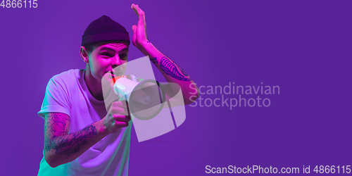 Image of Caucasian man\'s portrait isolated on purple studio background in neon light, flyer