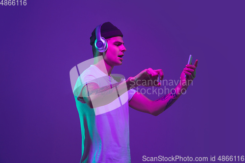 Image of Caucasian man\'s portrait isolated on purple studio background in neon light