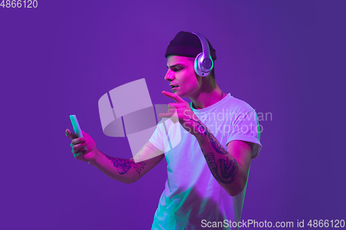 Image of Caucasian man\'s portrait isolated on purple studio background in neon light