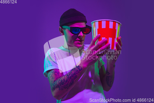 Image of Caucasian man\'s portrait isolated on purple studio background in neon light, cinema concept