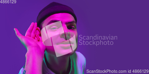 Image of Caucasian man\'s portrait isolated on purple studio background in neon light, flyer