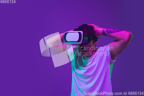 Image of Caucasian man\'s portrait isolated on purple studio background in neon light