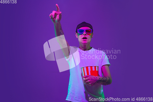 Image of Caucasian man\'s portrait isolated on purple studio background in neon light, cinema concept