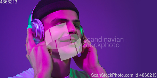 Image of Caucasian man\'s portrait isolated on purple studio background in neon light, flyer