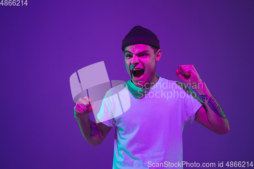 Image of Caucasian man\'s portrait isolated on purple studio background in neon light