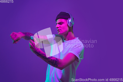 Image of Caucasian man\'s portrait isolated on purple studio background in neon light