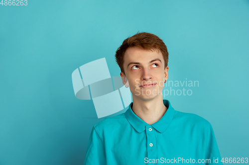 Image of Caucasian young man\'s monochrome portrait on blue studio background, emotinal and beautiful
