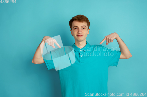 Image of Caucasian young man\'s monochrome portrait on blue studio background, emotinal and beautiful