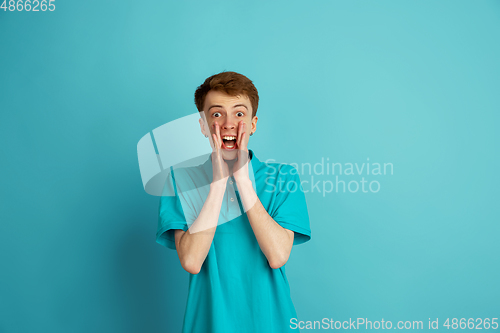 Image of Caucasian young man\'s monochrome portrait on blue studio background, emotinal and beautiful