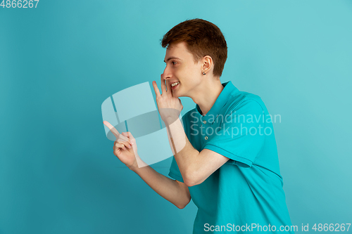 Image of Caucasian young man\'s monochrome portrait on blue studio background, emotinal and beautiful