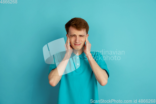 Image of Caucasian young man\'s monochrome portrait on blue studio background, emotinal and beautiful