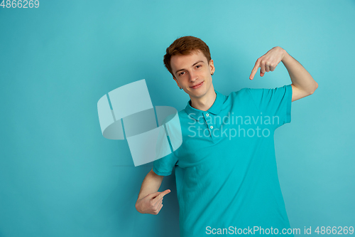 Image of Caucasian young man\'s monochrome portrait on blue studio background, emotinal and beautiful