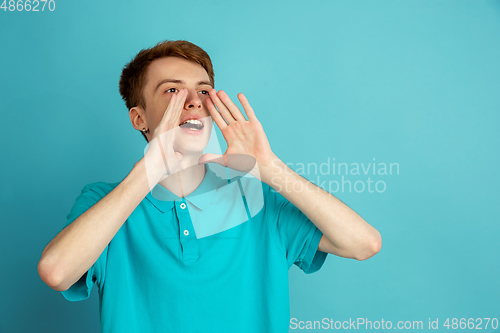 Image of Caucasian young man\'s monochrome portrait on blue studio background, emotinal and beautiful
