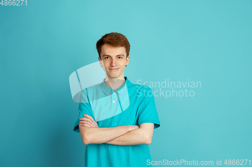 Image of Caucasian young man\'s monochrome portrait on blue studio background, emotinal and beautiful