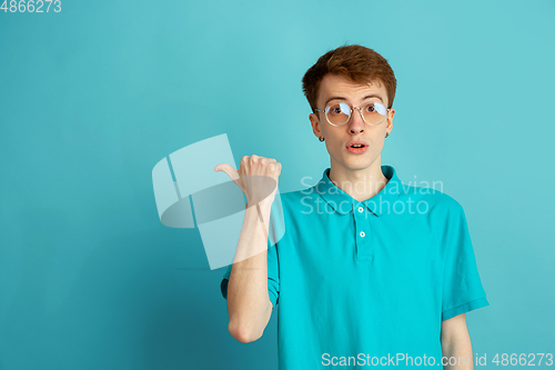 Image of Caucasian young man\'s monochrome portrait on blue studio background, emotinal and beautiful