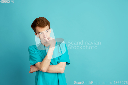 Image of Caucasian young man\'s monochrome portrait on blue studio background, emotinal and beautiful
