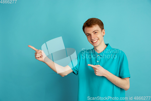 Image of Caucasian young man\'s monochrome portrait on blue studio background, emotinal and beautiful