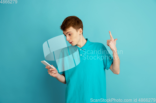 Image of Caucasian young man\'s monochrome portrait on blue studio background, emotinal and beautiful