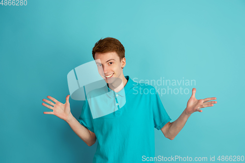 Image of Caucasian young man\'s monochrome portrait on blue studio background, emotinal and beautiful