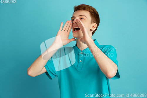 Image of Caucasian young man\'s monochrome portrait on blue studio background, emotinal and beautiful