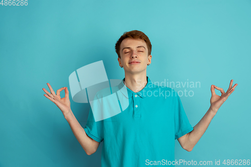 Image of Caucasian young man\'s monochrome portrait on blue studio background, emotinal and beautiful