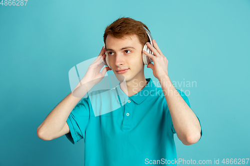 Image of Caucasian young man\'s monochrome portrait on blue studio background, emotinal and beautiful