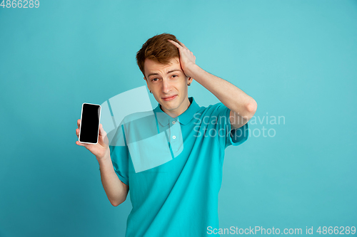 Image of Caucasian young man\'s monochrome portrait on blue studio background, emotinal and beautiful