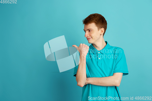 Image of Caucasian young man\'s monochrome portrait on blue studio background, emotinal and beautiful