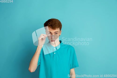 Image of Caucasian young man\'s monochrome portrait on blue studio background, emotinal and beautiful