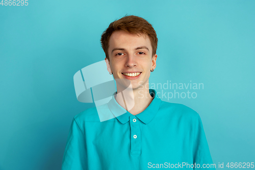 Image of Caucasian young man\'s monochrome portrait on blue studio background, emotinal and beautiful