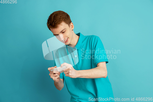 Image of Caucasian young man\'s monochrome portrait on blue studio background, emotinal and beautiful