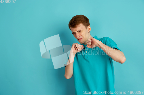 Image of Caucasian young man\'s monochrome portrait on blue studio background, emotinal and beautiful