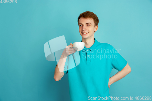 Image of Caucasian young man\'s monochrome portrait on blue studio background, emotinal and beautiful