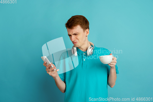 Image of Caucasian young man\'s monochrome portrait on blue studio background, emotinal and beautiful