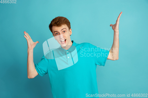 Image of Caucasian young man\'s monochrome portrait on blue studio background, emotinal and beautiful
