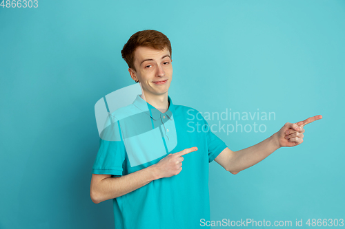 Image of Caucasian young man\'s monochrome portrait on blue studio background, emotinal and beautiful