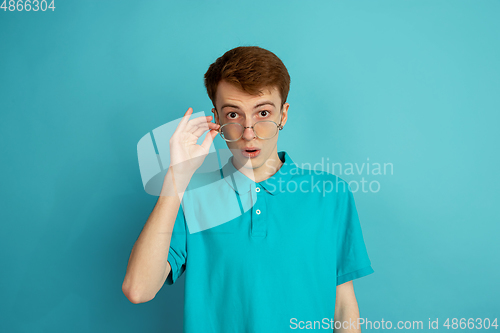 Image of Caucasian young man\'s monochrome portrait on blue studio background, emotinal and beautiful