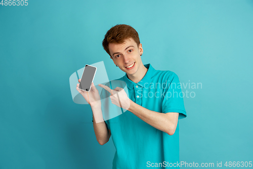 Image of Caucasian young man\'s monochrome portrait on blue studio background, emotinal and beautiful