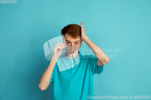 Image of Caucasian young man\'s monochrome portrait on blue studio background, emotinal and beautiful