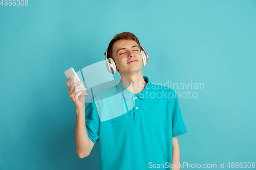 Image of Caucasian young man\'s monochrome portrait on blue studio background, emotinal and beautiful