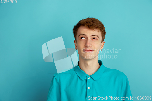 Image of Caucasian young man\'s monochrome portrait on blue studio background, emotinal and beautiful