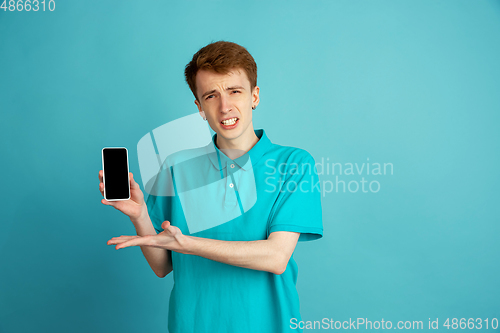 Image of Caucasian young man\'s monochrome portrait on blue studio background, emotinal and beautiful
