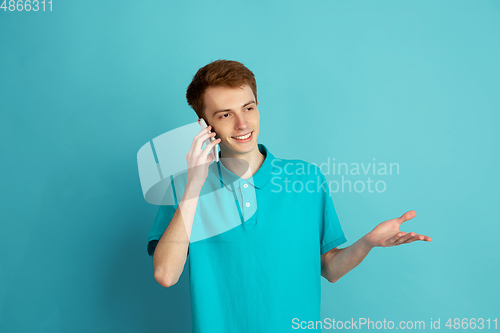 Image of Caucasian young man\'s monochrome portrait on blue studio background, emotinal and beautiful