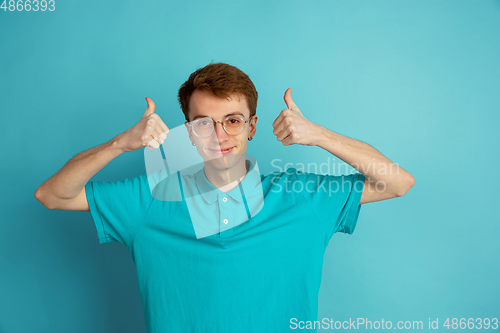 Image of Caucasian young man\'s monochrome portrait on blue studio background, emotinal and beautiful