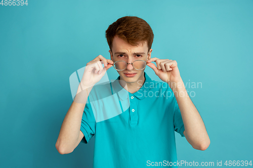 Image of Caucasian young man\'s monochrome portrait on blue studio background, emotinal and beautiful